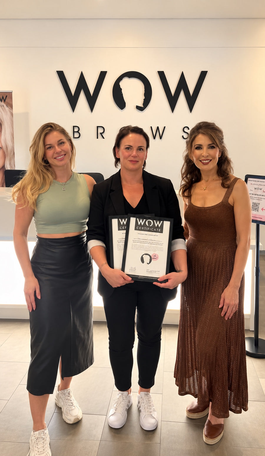 Absolventinnen vor dem WOWbrows Logo in der Akademie in Glienicke/Nordbahn